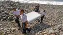 Foto ini diambil pada tanggal 29 Juli 2015, Polisi Perancis membawa potongan puing-puing dari pesawat yang diduga Malaysia Airlines MH370 di pantai Saint-Andre, Pulau Reunion. (AP Photo/Lucas Marie)