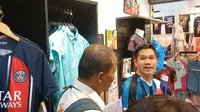 Seorang pengunjung sedang melakukan negosiasi dengan pedagang jersey di kawasan Asiatique The Riverfront, Bangkok, Thailand, Kamis (30/11/2023) malam WIB. (Bola.com/Hery Kurniawan)