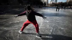 Aksi seorang warga saat bermain ice skating di sungai yang membeku di Beijing, China (21/1). Akibat membeku, Sungai ini menjadi objek wisata dadakan yang banyak diminati wisatawan. (AFP/Fred Dufour)