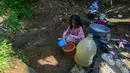 Seoarang anak mengambil air dari mata air yang  bercampur lumpur di Kampung Cijaura, Desa Cidokom, Bogor, Jawa Barat, Minggu (26/07/2026). (KLY/ Arie Basuki)