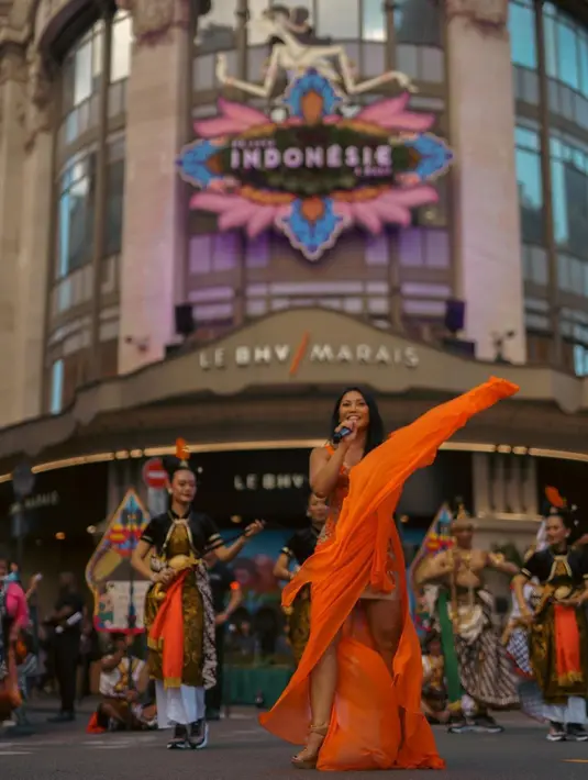 Anggun C Sasmi tampil dalam balutan khas Indonesia. Ia mengenakan dress oranye dengan outer hitam bercorak batik. (Instagram/anggun_cipta)