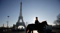 Seorang petugas polisi berpatroli di dekat Menara Eiffel di Paris,  Senin (30/12/2019). Pemerintah Prancis akan mengerahkan 100.000 petugas polisi untuk mengamankan ruang publik pada perayaan malam Tahun Baru di tengah aksi mogok yang sedang berlangsung. (AP/Christophe Ena)