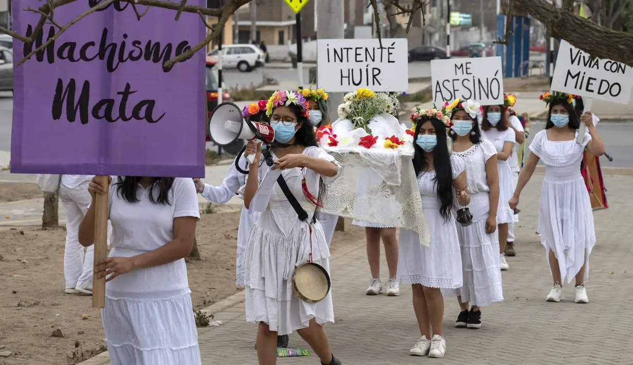 Rombongan teater Vichama melakukan prosesi kamar mayat berjudul "Kami Ingin Diri Sendiri Hidup!" sambil membawa tubuh tiruan dan menampilkan tanda-tanda kiasan pada malam Hari Anti Kekerasan Terhadap Perempuan di Villa El Salvador, Lima, Peru, 24 November 2021. (Cris BOURONCLE/AFP)