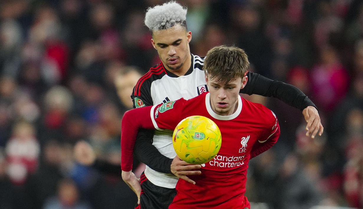 Bek Liverpool, Conor Bradley (depan) menguasai bola dibayangi bek Fulham, Antonee Robinson pada laga leg pertama babak semifinal Carabao Cup 2023/2024 di Anfield Stadium, Liverpool, Kamis (11/1/2024) dini hari WIB. (AP Photo/Jon Super)