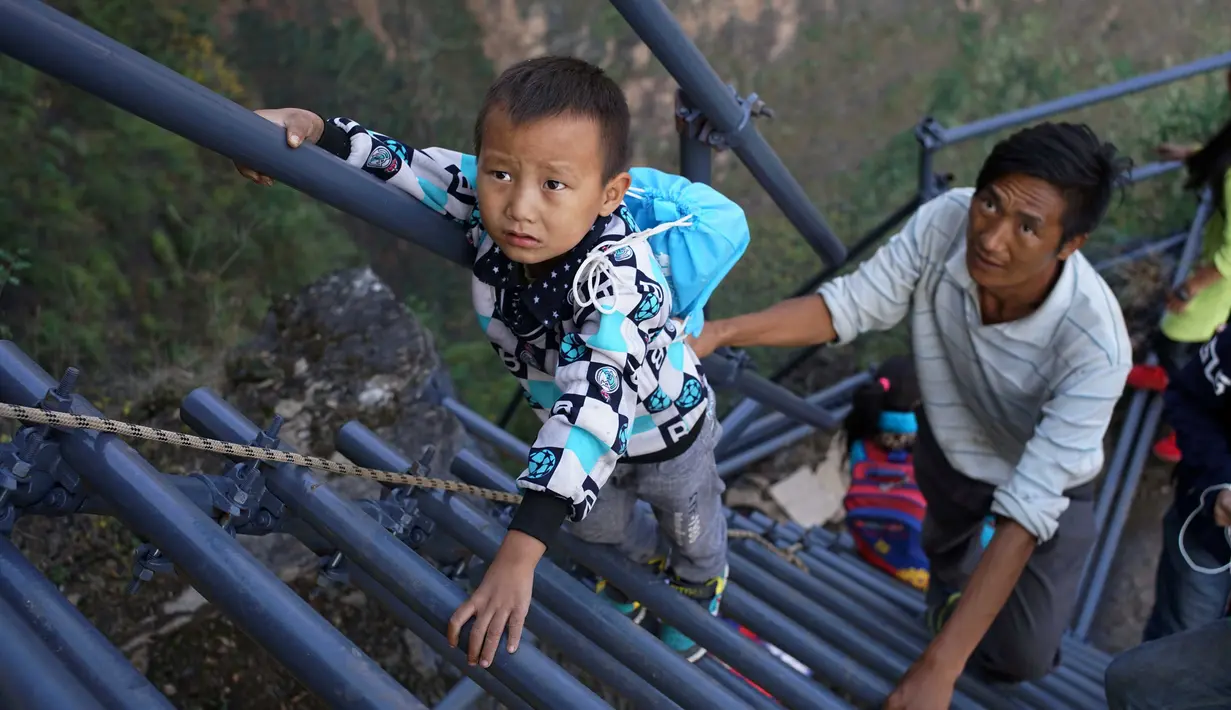 Sejumlah anak didampingi orang tua memanjat tangga baru menuju rumah yang berada di ketinggian 800 meter di Desa Atuleer, Tiongkok, Rabu (19/11). Pemerintah Tiongkok akhirnya membangun tangga untuk warga yang tinggal di desa tersebut. (REUTERS)