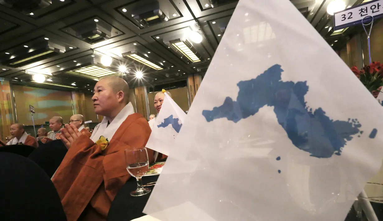 Seorang biksu wanita berdoa di samping bendera unifikasi selama Konferensi Perdamaian Bhikkhuni Buddha Dunia di Seoul, Korea Selatan (12/4). Mereka melakukan doa untuk persatuan Korea Utara dan Korea Selatan. (AP Photo / Ahn Young-joon)