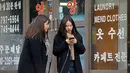 Dua wanita berbincang sambil berjalan di sepanjang jalan di Seoul, Korea Selatan (19/2). (AFP Photo/David Gannon)