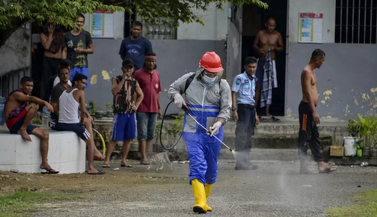 Seorang narapidana (kiri) menyemprotkan disinfektan sebagai bagian dari upaya penanggulangan virus corona COVID-19 di sebuah penjara di Banda Aceh (3/9/2020). (AFP Photo/Chaideer Mahyuddin)