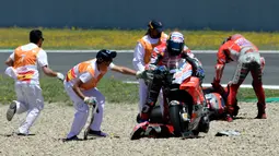 Petugas membantu pembalap Ducati, Andrea Dovizioso dan Jorge Lorenzo setelah mengalami tabrakan beruntun pada balapan MotoGP Spanyol 2018 di Sirkuit Jerez, Minggu (6/5). Mereka mengalami crash delapan lap sebelum bubaran.  (AFP/JAVIER SORIANO)