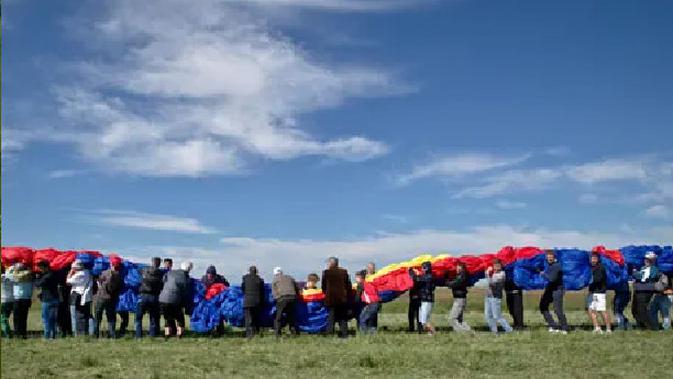 Penduduk desa membawa bendera besar di lapangan terbang Clinceni, selatan Bucharest, Rumania. (Vadim Ghirda/AP)