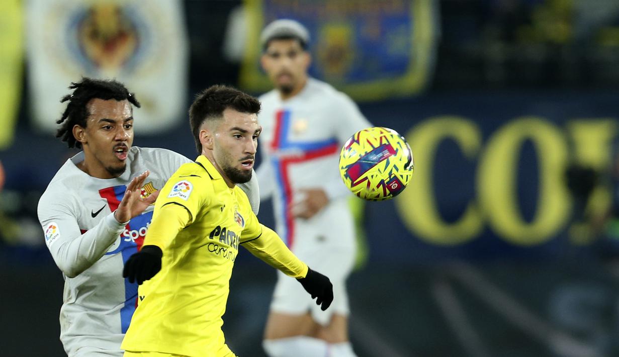 Bek Barcelona, Jules Kounde berusaha merebut bola dari pemain Villarreal, Alex Baena selama pertandingan lanjutan La Liga Spanyol di stadion Ceramica di Villarreal, Spanyol, Senin (13/2/2023). Barcelona berada di pucuk dengan koleksi 56 poin, unggul 11 poin atas tim peringkat kedua Real Madrid, namun Los Blancos baru memainkan 20 pertandingan. (AP Photo/Alberto Saiz)
