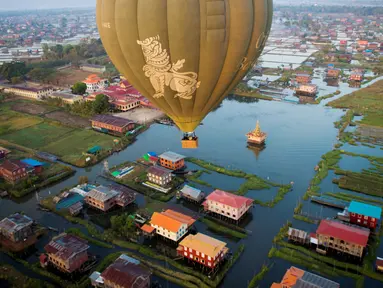 Balon udara terbang di atas rumah-rumah panggung kampung terapung Danau Inle, Negara Bagian Shan, Myanmar, Senin (18/2). Danau air tawar yang sangat luas ini menawarkan berbagai keindahan. (Ye Aung THU/AFP)