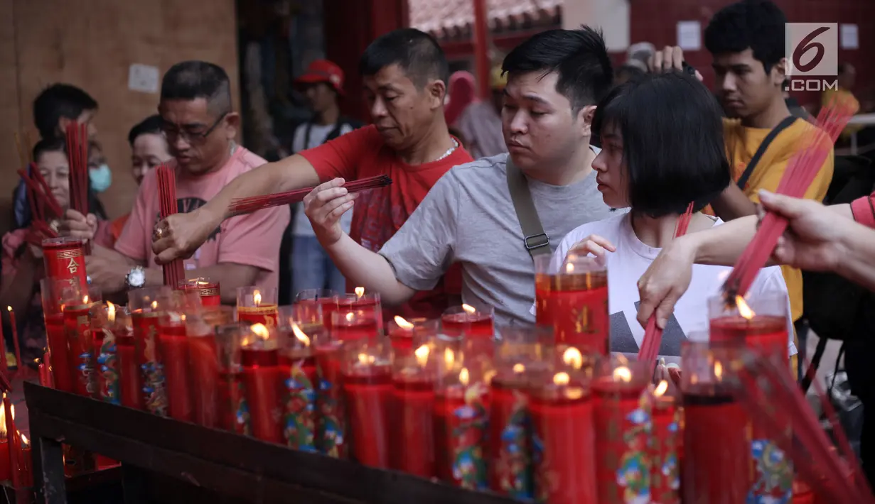 Warga keturunan Tionghoa menyalakan lilin saat bersembahyang Imlek 2569 di Vihara Dharma Bhakti, Petak Sembilan, Jakarta Barat, Jumat (16/2). Imlek 2569 jatuh pada shio anjing atau bisa disebut sebagai tahun anjing. (Liputan6.com/Arya Manggala)