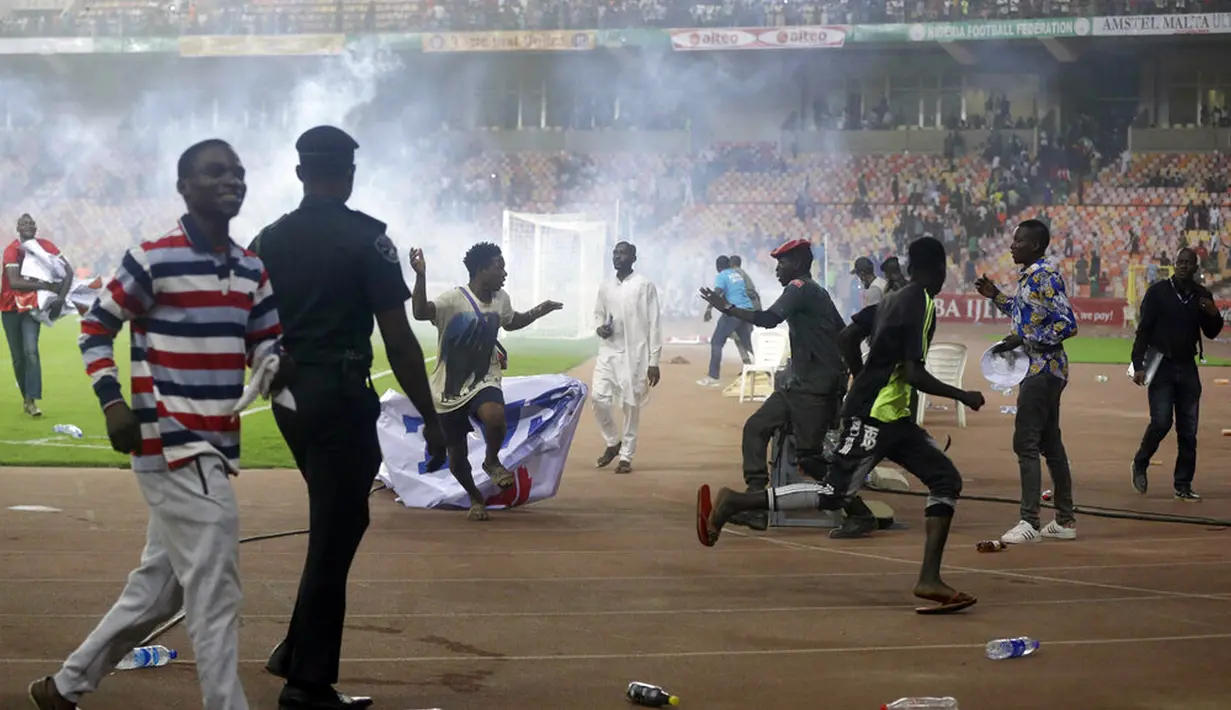 Polisi menembakkan gas air mata untuk mengejar penyerbu lapangan pada akhir pertandingan kualifikasi Piala Dunia 2022 antara Ghana Vs Nigeria di Stadion Moshood Abiola, Abuja, Nigeria, 29 Maret 2022. Fans Nigeria ngamuk setelah gagal lolos ke Piala Dunia 2022. (AP Photo/Sunday Alamba)