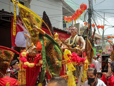 Tatung pria melakukan atraksi dalam Festival Cap Go Meh 2023 di kawasan Glodok, Jakarta, Minggu (5/2/2023). Sebanyak 23 joli atau tandu diarak keliling sebagai penutup rangkaian perayaan Tahun Baru Imlek yang dilaksanakan pada tanggal ke-15 bulan pertama penanggalan Tionghoa. (Liputan6.com/Faizal Fanani)
