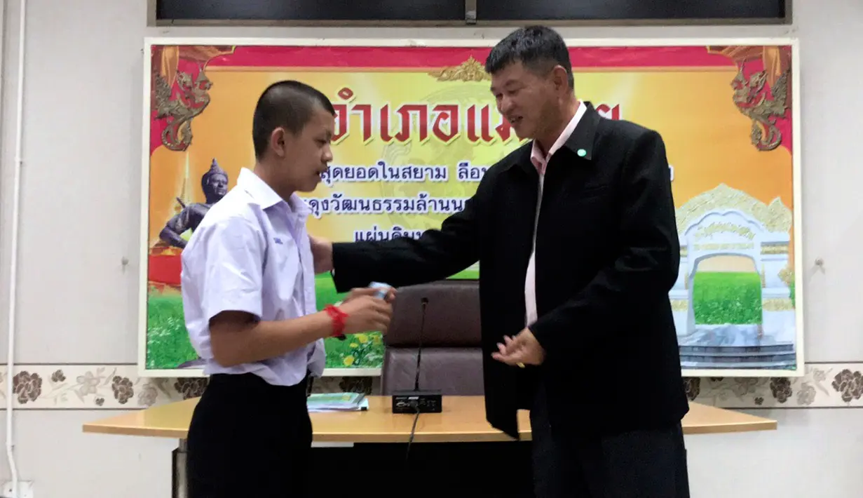 Salah seorang remaja, Pornchai Kamluang menerima kartu identitas sebagai warga negara Thailand di distrik Mae Sai, Rabu (8/8). Korban gua Thailand tersebut selama ini hidup tanpa memiliki status kewarganegaraan (Chiang Rai Public Relations Office via AP)