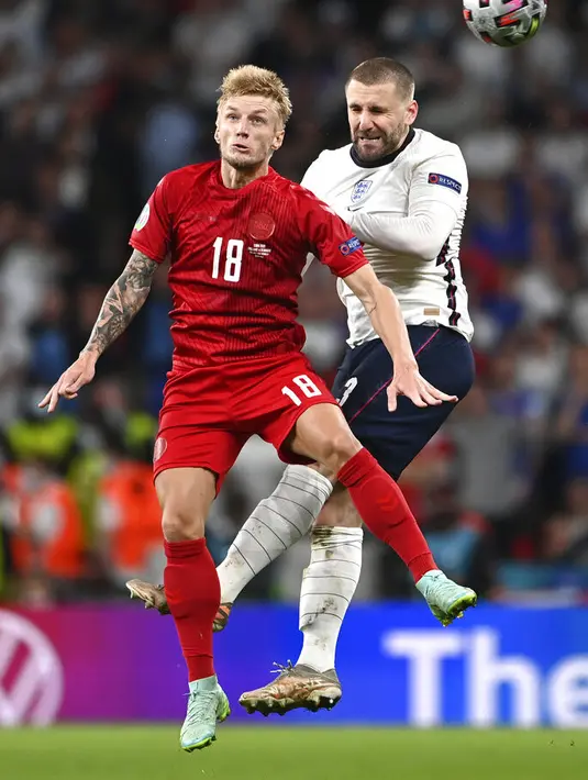 Bek Inggris, Luke Shaw berebut bola dengan pemain Denmark, Daniel Wass pada pertandingan semifinal Euro 2020 di Stadion Wembley, London, Kamis (8/7/2021). Inggris menang atas Denmark dengan skor 2-1. (Andy Rain/Pool via AP)