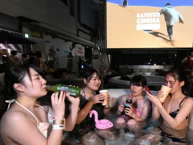 Pengunjung menikmati menonton film sambil berendam di Bathtub Cinema di atap gedung kawasan Shibuya, Tokyo, 17 Agustus 2018. Bathtub Cinema merupakan solusi kreatif yang ditawarkan oleh Afro&Co. untuk menikmati Tokyo di musim panas. (AFP/Kazuhiro NOGI)