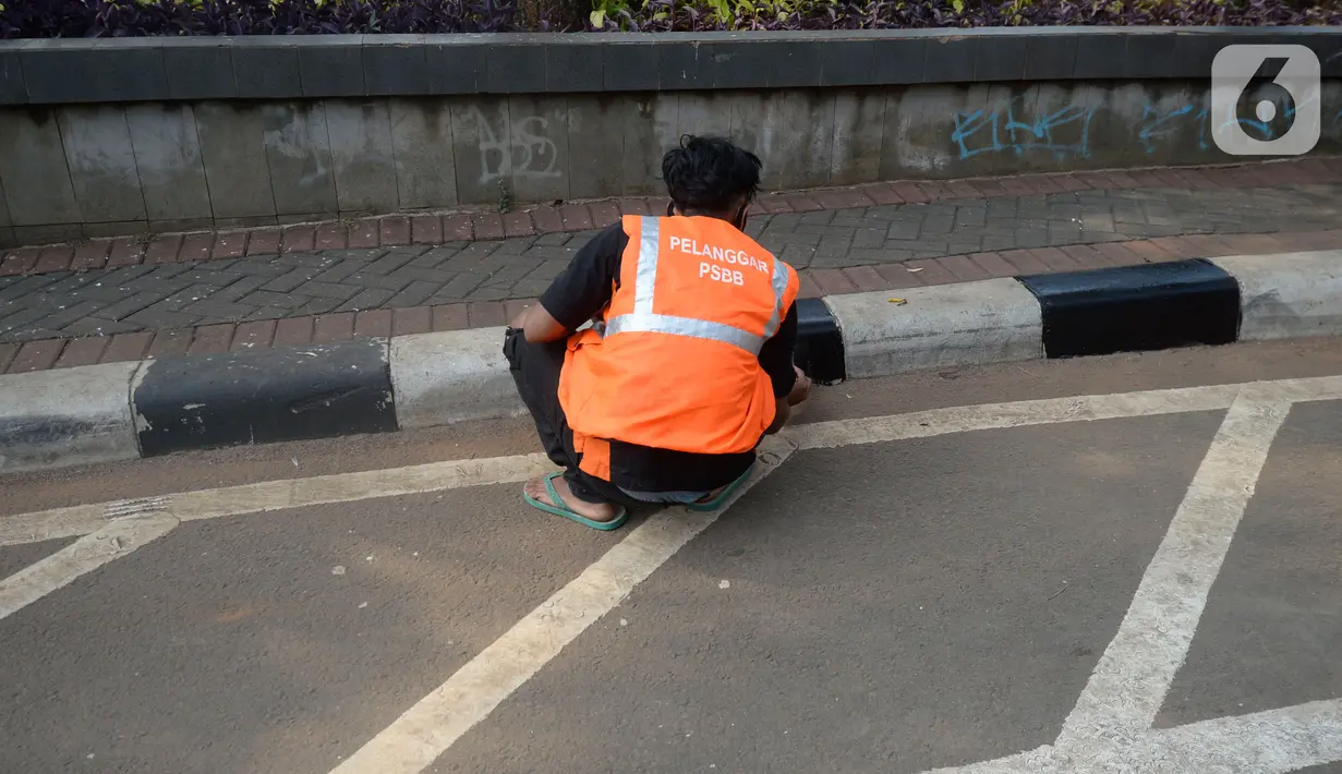 Warga terkena sanksi sosial mengcat pembatas jalan kepada warga pelanggar karena tidak menggunakan masker di Lebak Bulus, Jakarta, senin (14/09/2020). Pemerintah Provinsi DKI Jakarta memperketat kembali PSBB karena kasus Covid-19 terus mengalami peningkatan. (merdeka.com/Dwi Narwoko)