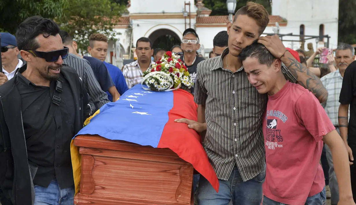 Kesedihan keluarga dan kerabat saat mengantarkan jenazah Jose Francisco Guerrero untuk dimakamkan di San Cristobal, Tachira State, Venezuela (19/5). (AFP/Luis Robayo)