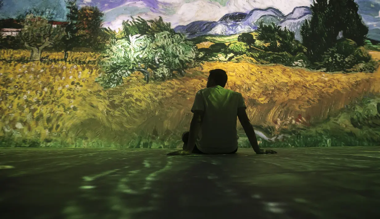 Seorang tamu duduk di pameran multimedia Van Gogh Live 8K yang menampilkan proyeksi lukisan seniman Belanda Vincent Willem van Gogh, pada pembukaan pameran untuk media dan tamu, di Rio de Janeiro, Brasil, Rabu (27/7/2022). (AP Photo / Bruna Prado)