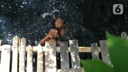 Anak-anak berenang di Kali Cilemahabang yang menghitam di kawasan Karangbahagia, Kabupaten Bekasi, Jawa Barat, Selasa (7/9/2021). Menurut warga sekitar, Kali Cilemahabang menghitam akibat tercemar limbah industri sejak lima tahun lalu. (Liputan6.com/ Herman Zakharia)