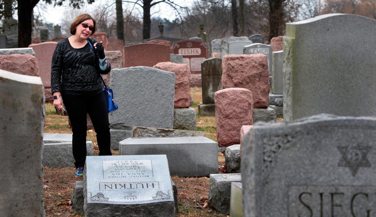 Sally Amon, melihat batu nisan neneknya yang dirusak di Chesed Shel Emeth Cemetery di University City, St Louis, Missouri, (21/2). Setidaknya lebih dari 100 batu nisan rusak di pekuburan itu. (Robert Cohen /St. Louis Post-Dispatch via AP)
