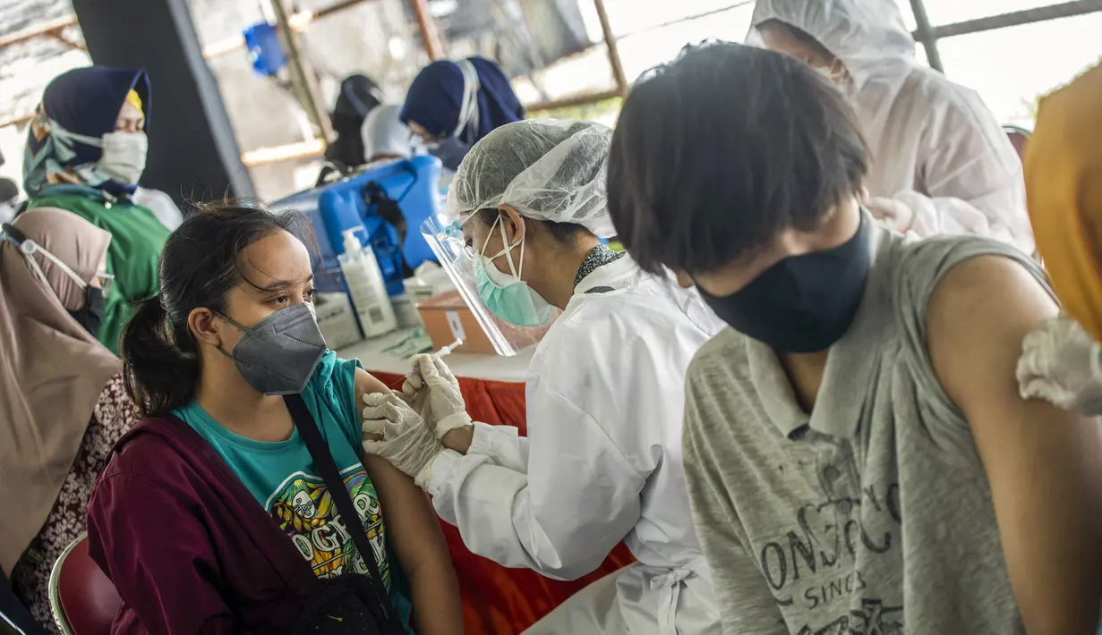Warga menerima vaksin virus corona COVID-19 Sinovac di klinik vaksinasi massal darurat di lapangan sepak bola di Surabaya, Jawa Timur, Selasa (6/7/2021). Indonesia tengah memerangi gelombang infeksi baru yang belum pernah terjadi sebelumnya. (JUNI KRISWANTO/AFP)