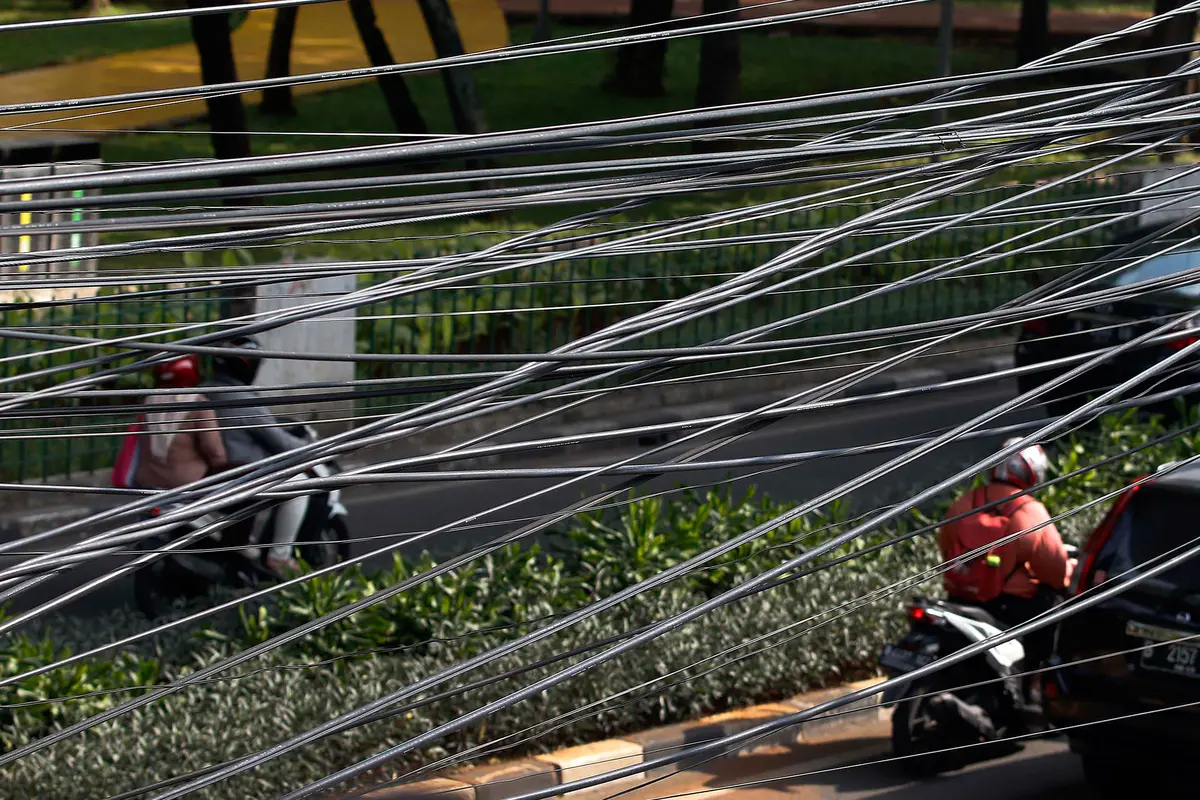 Kabel fiber optik yang semrawut di jalan Ibu Kota Jakarta kembali memakan korban. Kali bahkan menyebabkan seorang pengemudi ojek online (ojol) meninggal dunia.