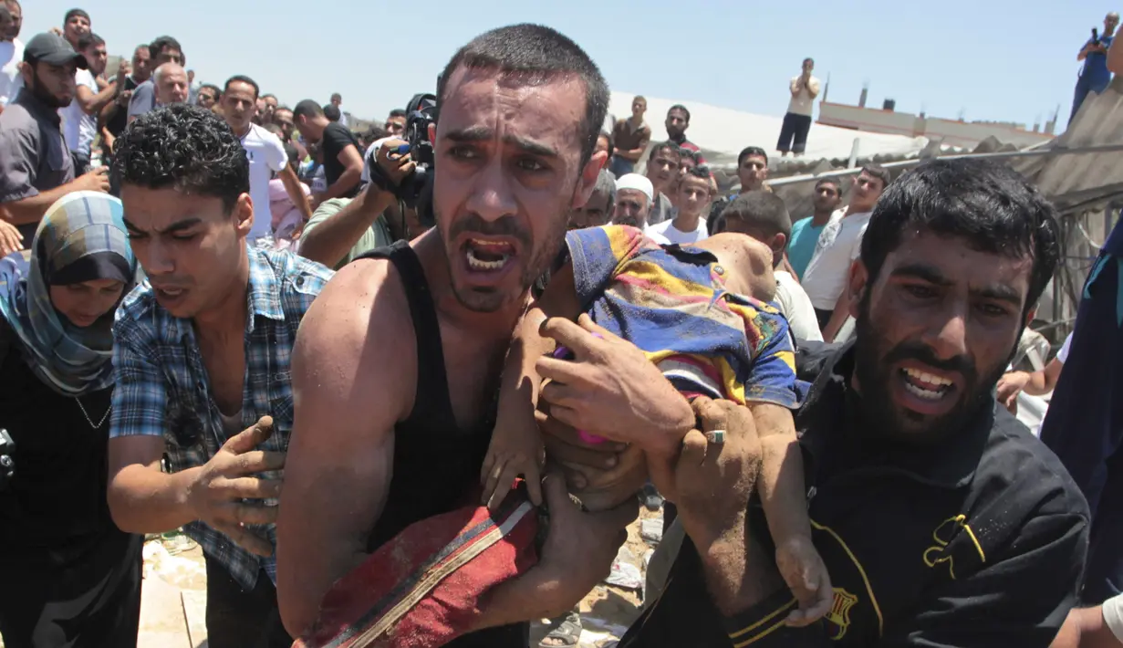 Warga menggendong seorang bocah yang tewas terkena serangan udara Israel di Gaza, Palestina, Rabu (9/7/14). (REUTERS/Ashraf Amrah)