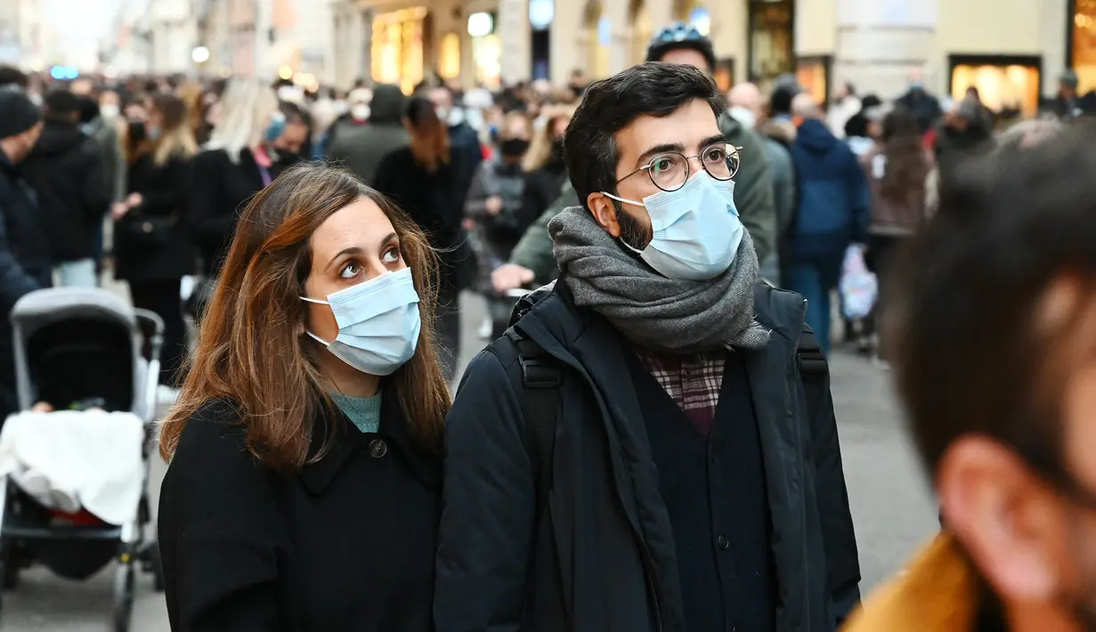 Orang-orang memakai masker di sepanjang jalan perbelanjaan mewah Via Condotti di pusat kota Roma, Italia, Minggu (5/12/2021). Kota Roma memberlakukan kewajiban penggunaan masker di ruang terbuka pusat kota dan area perbelanjaan sibuk lainnya hingga 31 Desember mendatang. (Vincenzo PINTO/AFP)