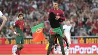 Ada momen menarik yang terjadi pada laga Kualifikasi Euro 2024 antara Portugal menghadapi Bosnia Herzegovina di Luz Stadum, Lisbon, Portugal, Minggu (18/6/2023) dini hari WIB. Di tengah laga, seorang penyusup lapangan memasuki arena pertandingan sambil mengibarkan bendera Portugal. Tak cuma berlari, pemuda berbadan kurus tersebut pun menghampiri Cristiano Ronaldo, lantas memperagakan selebrasi ikonik "siuuu" di depan sang megabintang. Bahkan sang penyusup sempat mengangkat CR-7 ke udara sebelum akhirnya ia kembali berlari menghindari kejaran petugas keamanan, hingga akhirnya ia menghentikan aksinya di pinggir lapangan sambil melakukan selebrasi "siuuu". (AP Photo/Armando Franca)