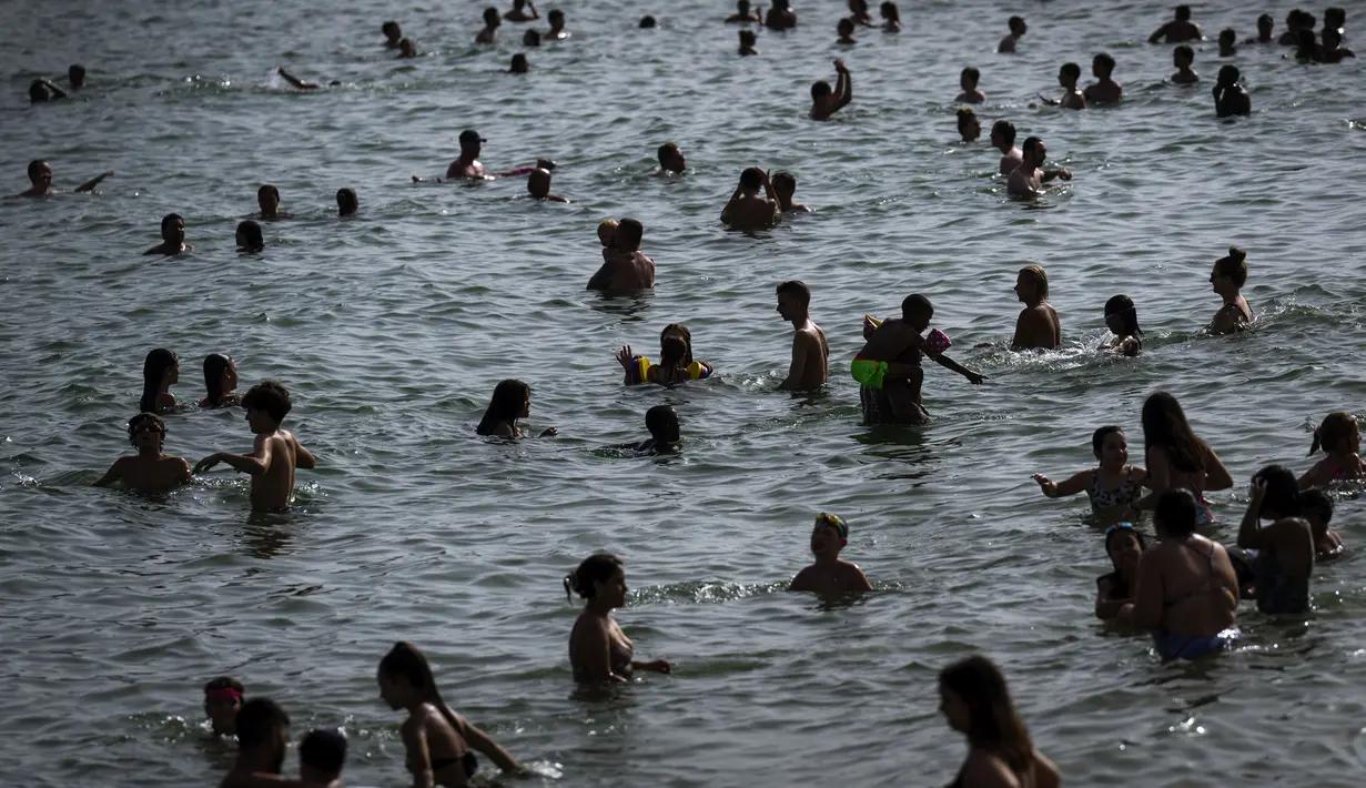Orang-orang mendinginkan diri di pantai di Barcelona, ​​​​Spanyol, Rabu, 12 Juli 2023. (AP Photo/Emilio Morenatti)