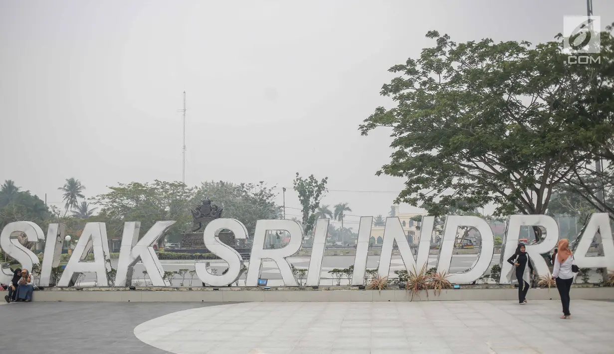 Sejumlah wanita berpose saat mengunjungi alun-alun Kabupaten Siak, Riau, Kamis (12/9/2019). Asap pekat kebakaran lahan gambut tersebut selain mengganggu kesehatan serta mencemari udara sehingga kualitasnya turun ke status tidak sehat. (Liputan6.com/Faizal Fanani)