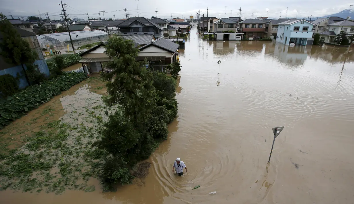 Seorang pria berjalan di luapan banjir dari Sungai Kinugawa di Joso, prefektur Ibaraki, Jepang, Kamis (10/9). Banjir yang disebabkan topan Etau ini mengakibatkan satu orang hilang dan 90 ribu lebih warga diperintahkan untuk mengungsi. (REUTERS/Issei Kato)