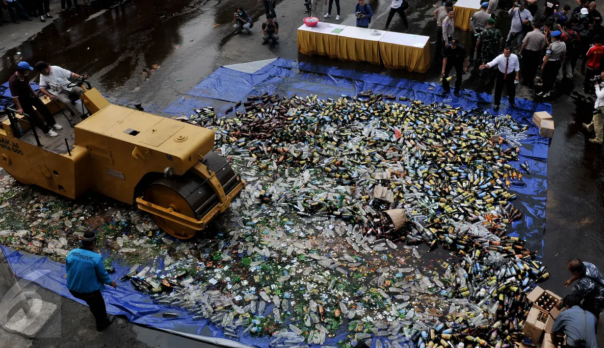 Petugas mengoperasikan alat berat untuk menghancurkan 10.286 ribuan botol minuman keras di halaman Mapolsek Palmerah, Jakbar, Senin (15/6/2015). (Liputan6.com/Johan Tallo)