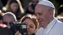 Seorang wanita mengambil foto selfie bersama Paus Fransiskus dalam kunjungannya ke St Mary Josefa di Roma, Italia, Minggu (19/2). (AFP Photo/TIZIANA FABI)