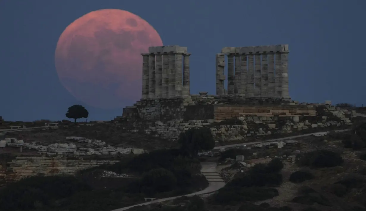 Bulan Purnama Stroberi atau Strawberry Full Moon muncul di belakang Kuil Poseidon marmer kuno di Cape Sounion, sekitar 70 Km selatan kota Athena, Yunani, Kamis (24/6/2021). Strawberry Full Moon adalah istilah yang diambil dari cerita tradisi dari suku-suku asli Amerika (AP Photo/Petros Giannakouris)