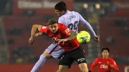 Bek Mallorca Pablo Maffeo melompat saat berebut bola dengan gelandang Barcelona Ferran Jutgla pada jornada ke-19 Liga Spanyol di Visit Mallorca Estadi, Senin (3/1/2022) dini hari WIB. Barcelona menang 1-0 berkat gol tunggal Luuk de Jong. (AP Photo/Francisco Ubilla)