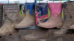 Sepatu boot berlumpur yang mengering tergantung pada hari kelima Festival Glastonbury di arena Worthy Farm, Inggris, 26 Juni 2017. Penyelenggaraan festival musik terbesar di dunia itu menyisakan sampah yang berserakan di seluruh arena. (Andy Buchanan/AFP)