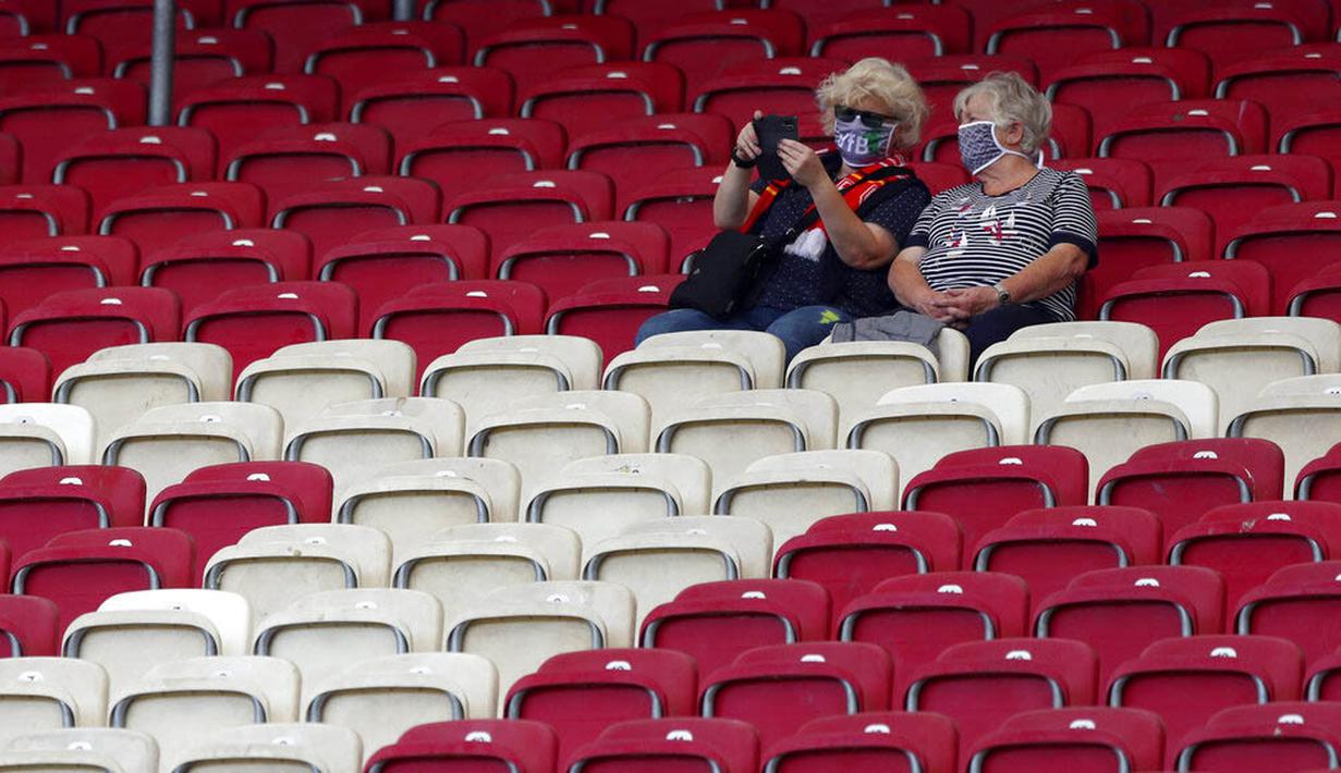 Dua orang penonton saat menyaksikan pertandingan antara  VfB Stuttgart melawan SC Freiburg pada laga Bundesliga, Sabtu (19/9/2020). Sejumlah liga di Eropa telah mengijinkan fans menonton langsung pertandingan di stadion. (AP Photo/Matthias Schrader)