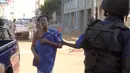 Petugas mengawal seorang sandera yang berhasil dibebaskan dari Hotel Radisson Blu di Bamako, Mali, Jumat (20/11). Kelompok militan Islam menyerbu hotel mewah tersebut dan  menyandera lebih dari 100 orang tamu serta staf hotel. (AFP PHOTO/Habibou Kouyate)