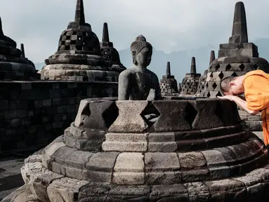 Seorang biksu Buddha berdoa di depan patung di salah satu stupa Candi Borobudur di Magelang, Jawa Tengah, pada 10 Mei 2025. (YASUYOSHI CHIBA/AFP)
