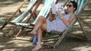 Seorang wanita membaca buku di kursi lipat pada saat cuaca hangat di taman Regents, London, Inggris, (24/8). (REUTERS/Neil Hall)