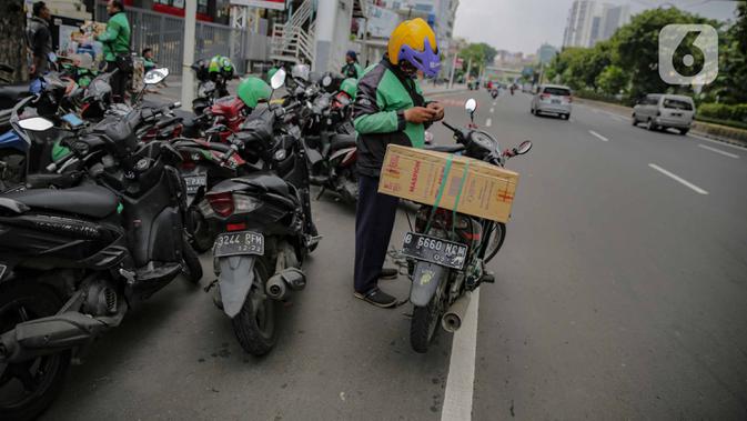 Pengemudi ojek online membawa barang pesanan yang akan diantar di kawasan Kenari Mas, Jakarta, Senin (13/4/2020). Walaupun regulasi pengangkutan penumpang untuk ojek  online masih belum jelas, tampak sejumlah pengemudi motor ojek online lebih memilih mengangkut barang. (Liputan6.com/Faizal Fanani)