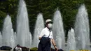 Seorang pria yang mengenakan masker pelindung untuk membantu mengekang penyebaran virus corona berjalan melalui taman di Tokyo (21/4/2021). Ibukota Jepang mengonfirmasi lebih dari 840 kasus virus corona baru pada hari Rabu. (AP Photo/Eugene Hoshiko)