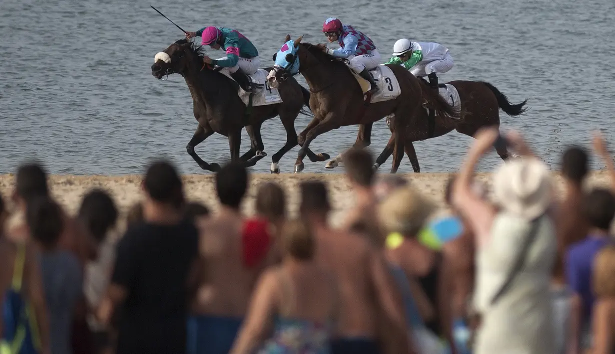 Jocky memacu kudanya dipinggir pantai pada ajang Annual Beach Horse Race di Sanlucar de Barrameda, Cadiz, (27/8/2016). (AFP/Jorge Guerrero)