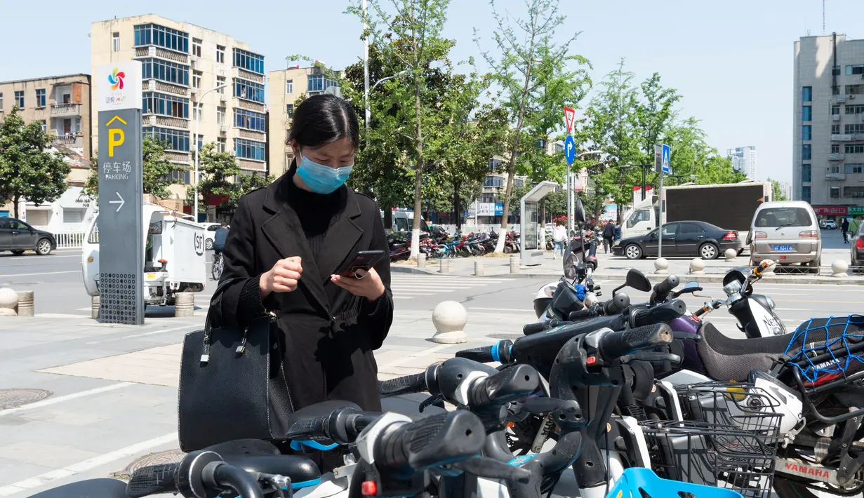 Seorang warga memindai kode respons cepat (QR) pada layanan berbagi sepeda listrik dengan ponsel pintar di Distrik Fancheng di Kota Xiangyang, Provinsi Hubei, China tengah (24/4/2020). (Xinhua/Xie Jianfei)
