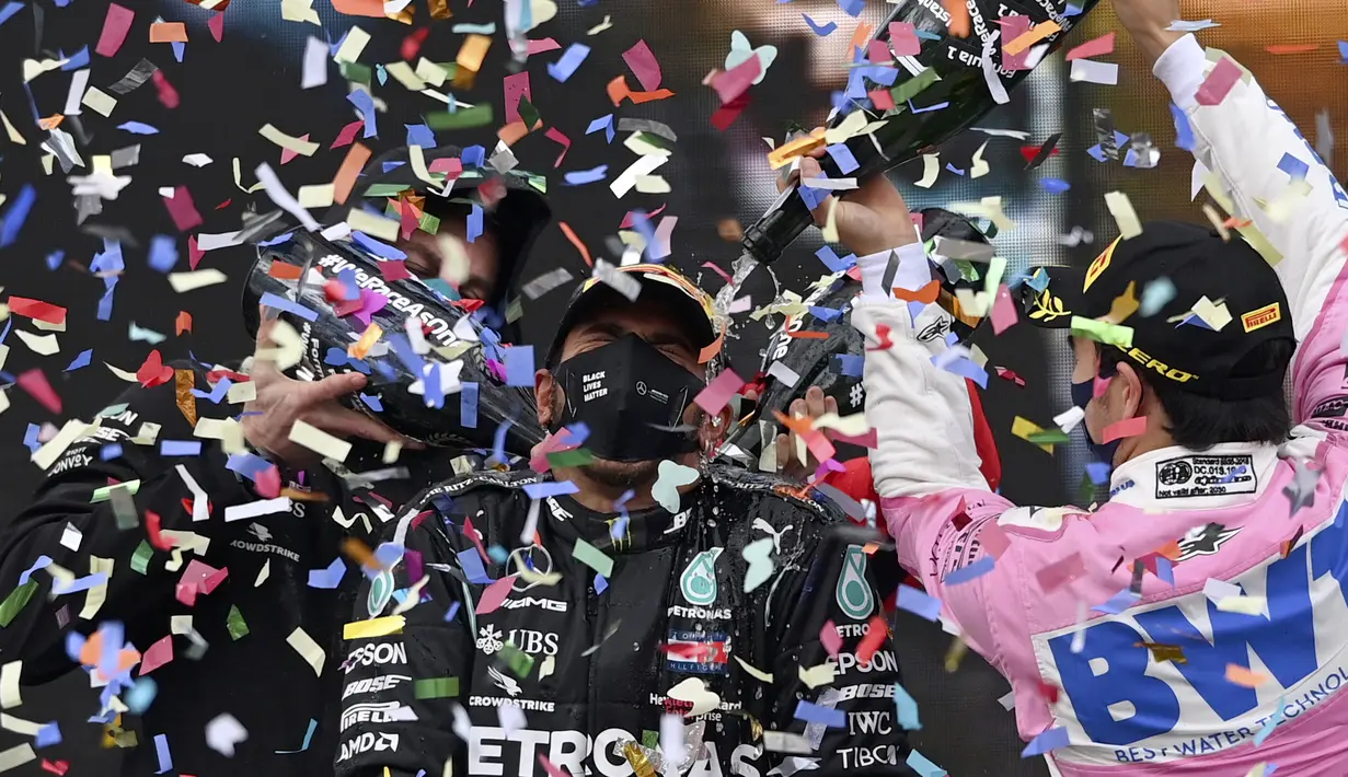 Pembalap Mercedes, Lewis Hamilton disemprotkan sampanye oleh pembalap Racing Point, Sergio Perez saat merayakan Juara Dunia Formula 1 2020 di sirkuit balap Istanbul Park di Istanbul, Minggu (15/11/2020). Ini jadi gelar ke-7 yang berhasil dicapai sepanjang karirnya. (Ozan Kose/Pool via AP)