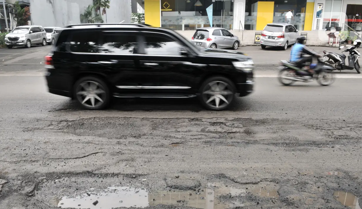 Kendaraan melintas dekat jalan berlubang di kawasan Kelapa Gading, Jakarta, Minggu (1/3/2020). Kepala Dinas Bina Marga DKI Jakarta Hari Nugroho mengatakan banjir pada Februari 2020 merusak 495 jalan Ibu Kota dengan 3.290 titik lubang yang tersebar di lima wilayah. (merdeka.com/Iqbal Nugroho)